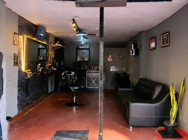 Interior do Christians Barber Studio, com área de atendimento e sofá.